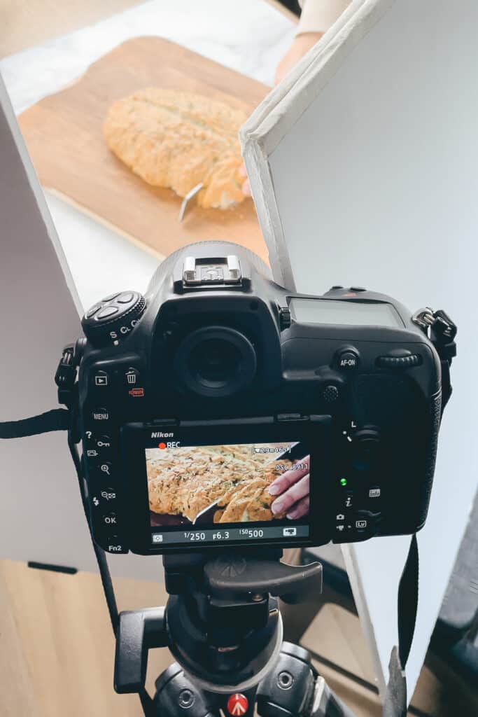 a camera on a tripod recording someone cutting bread.